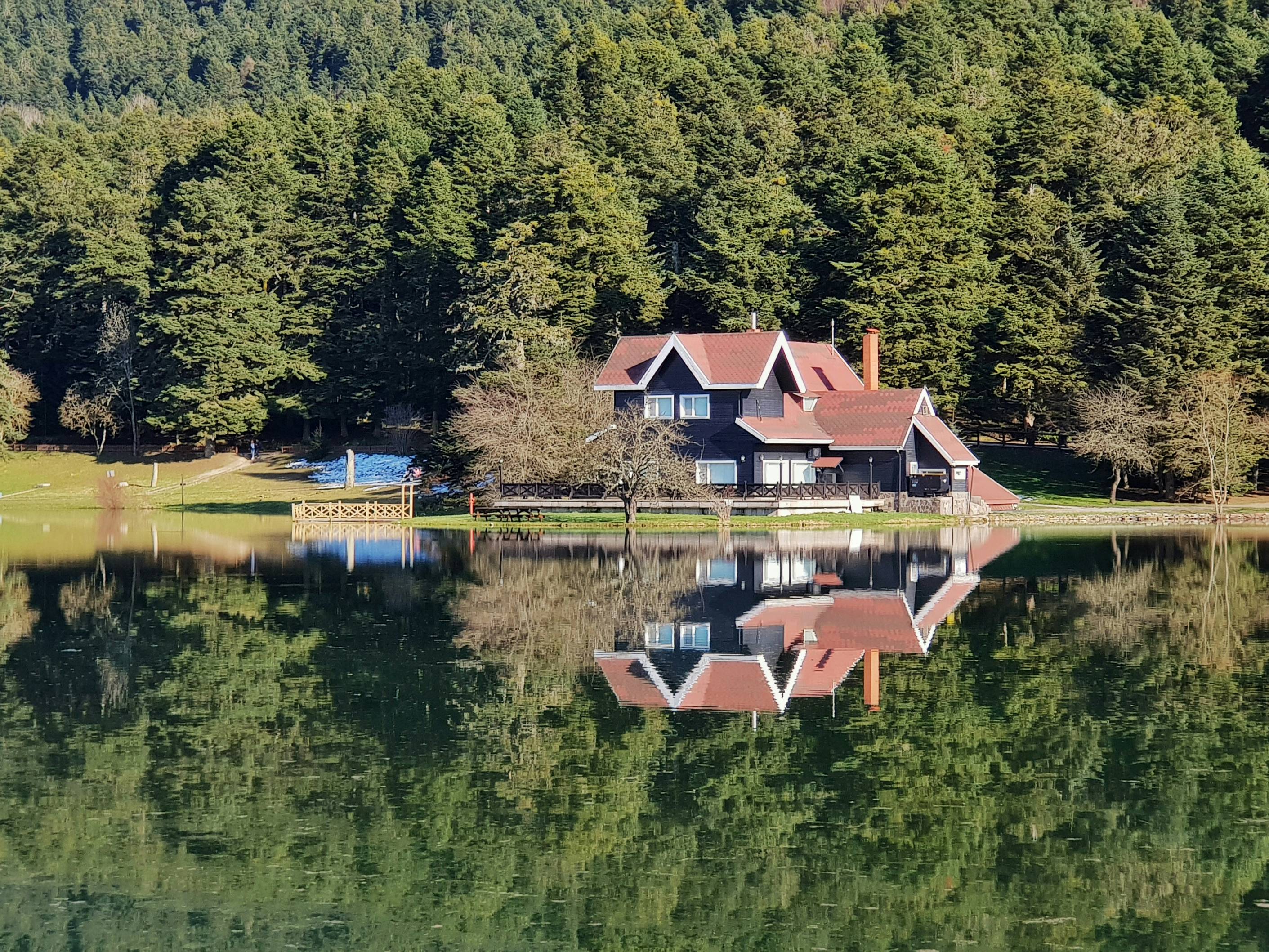 a house sitting on top of a lake surrounded by trees