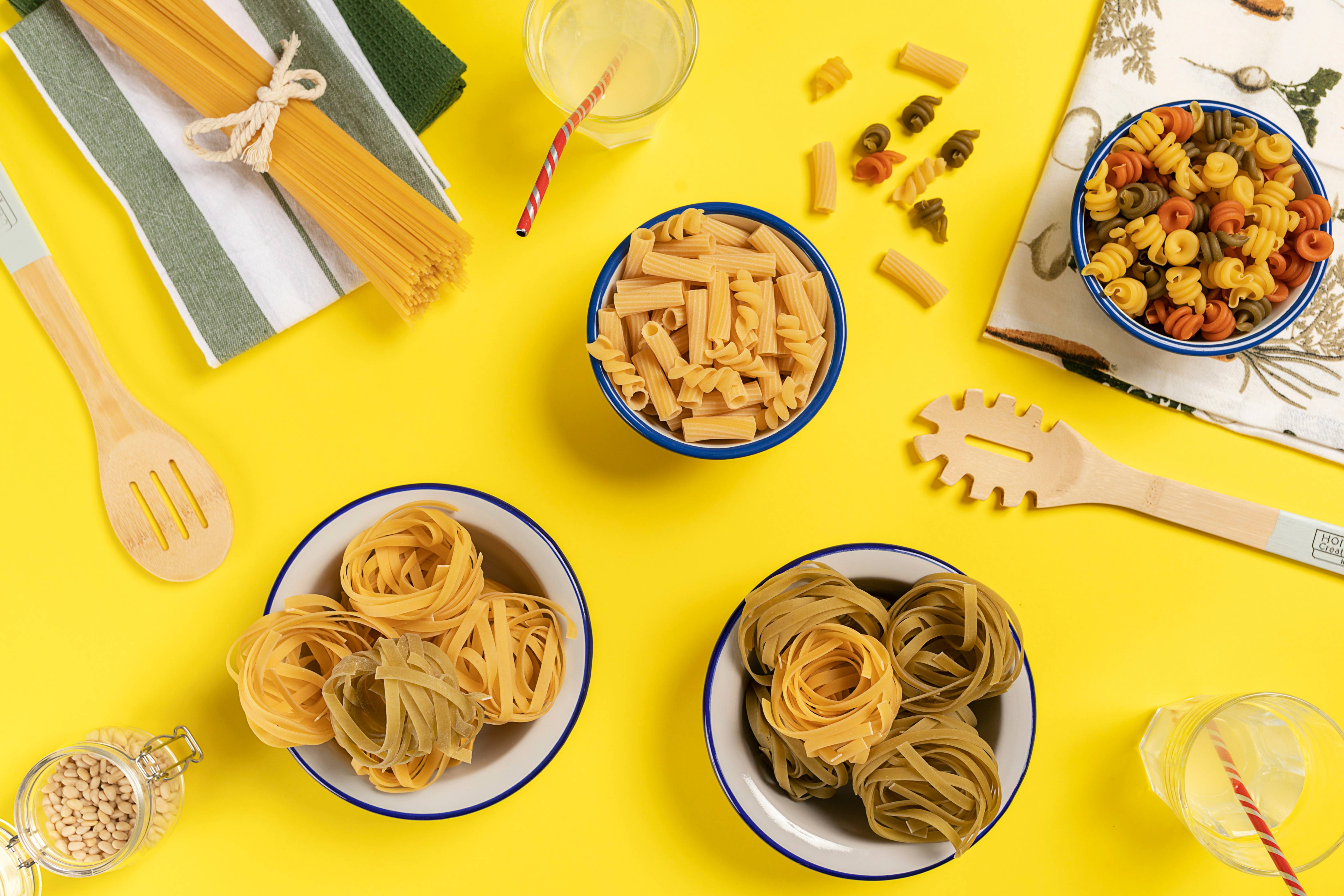 three bowls of pasta sit on a yellow surface