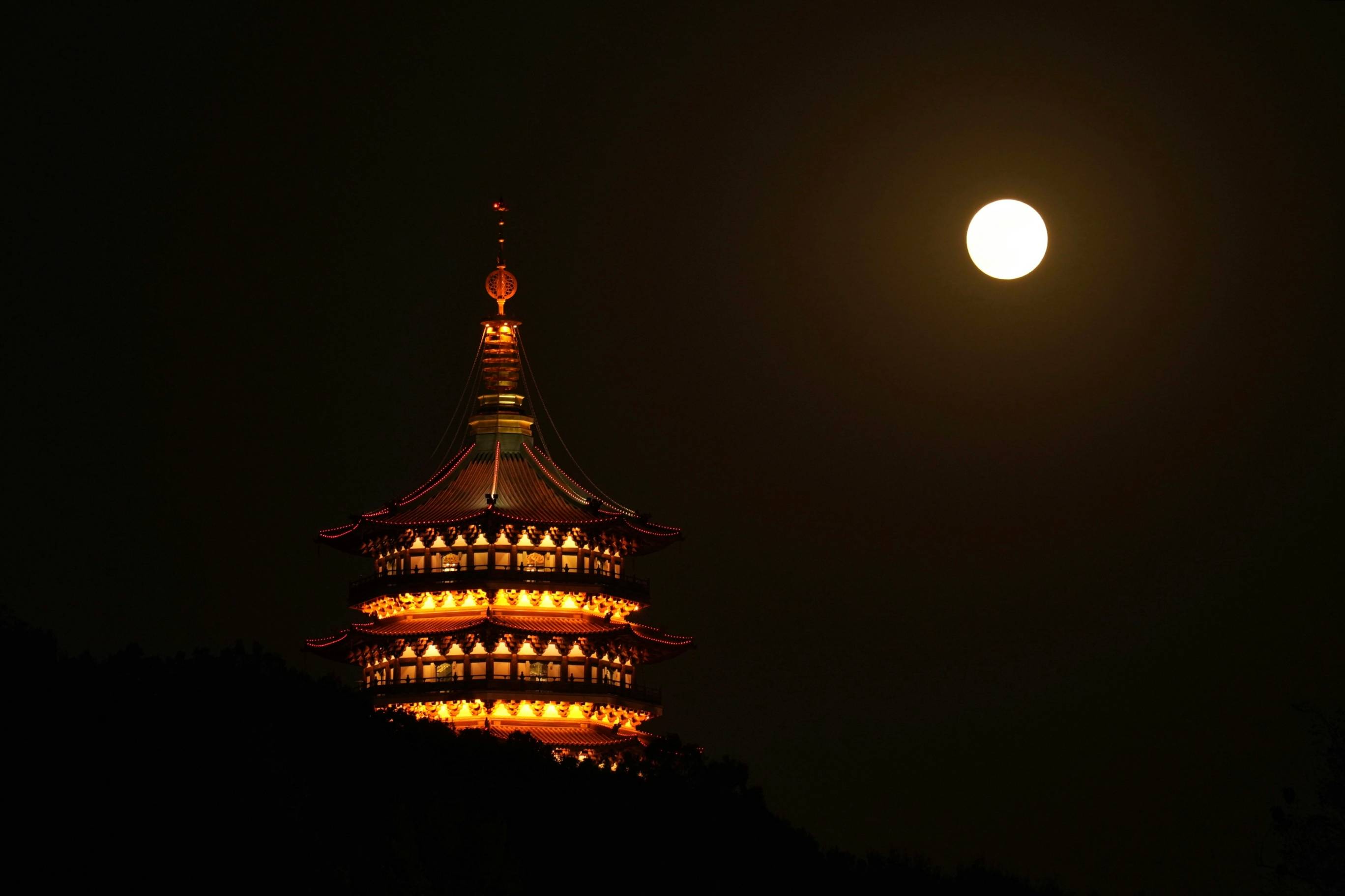 Pagoda shines under the moon in the night.