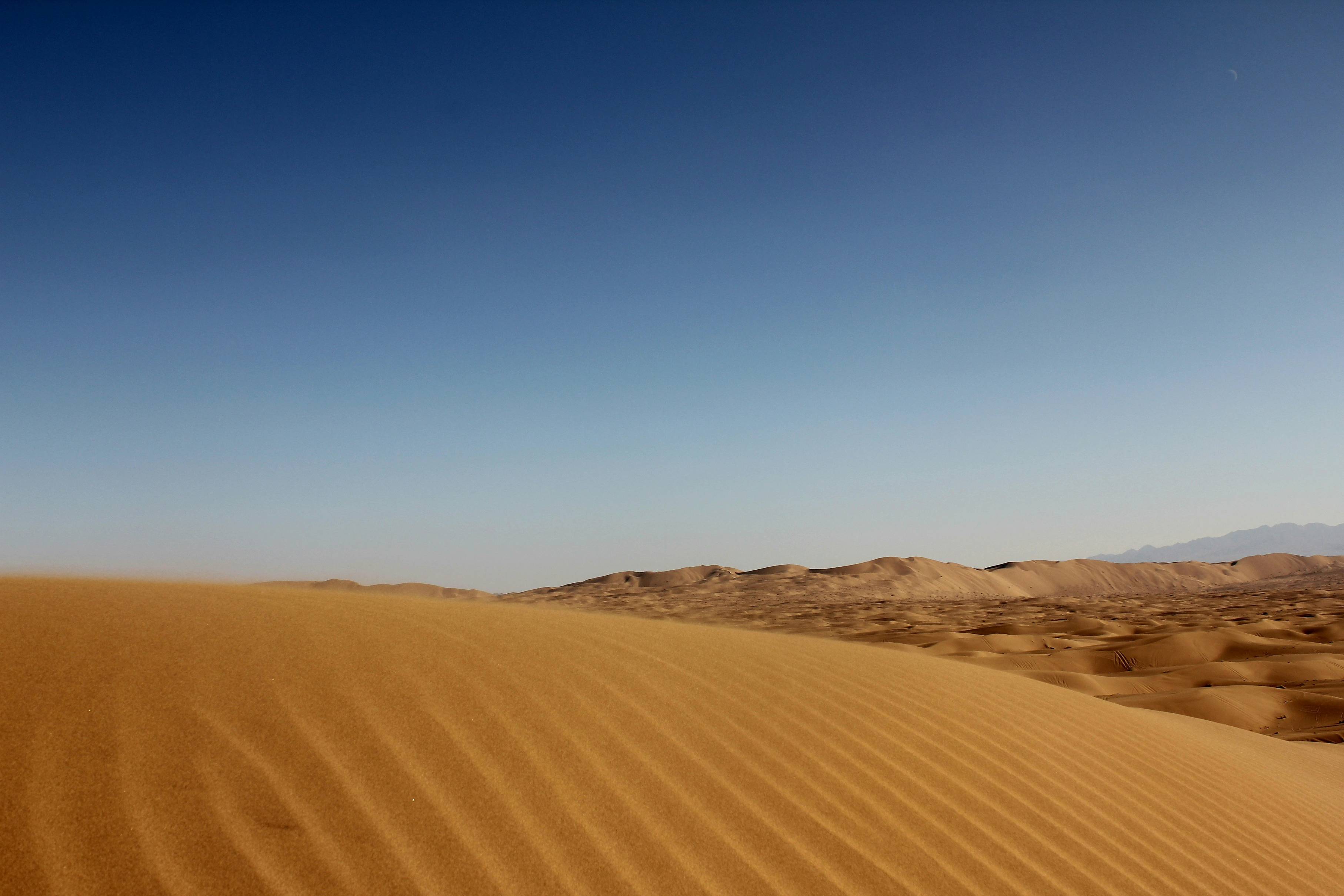 a desert with sand dunes and mountains in the background